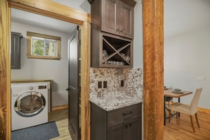 A compact kitchen with a built-in washing machine, dark wooden cabinets, and a marble countertop. - Pagosa Springs mountain-modern 4BR house with hot tub, deck, fireplace, and forest views; sleeps 8. (Pagosa Springs)