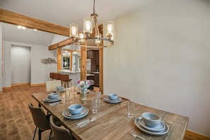 A dining area with a wooden table set for four, a chandelier, and a view into the kitchen. - Pagosa Springs mountain-modern 4BR house with hot tub, deck, fireplace, and forest views; sleeps 8. (Pagosa Springs)
