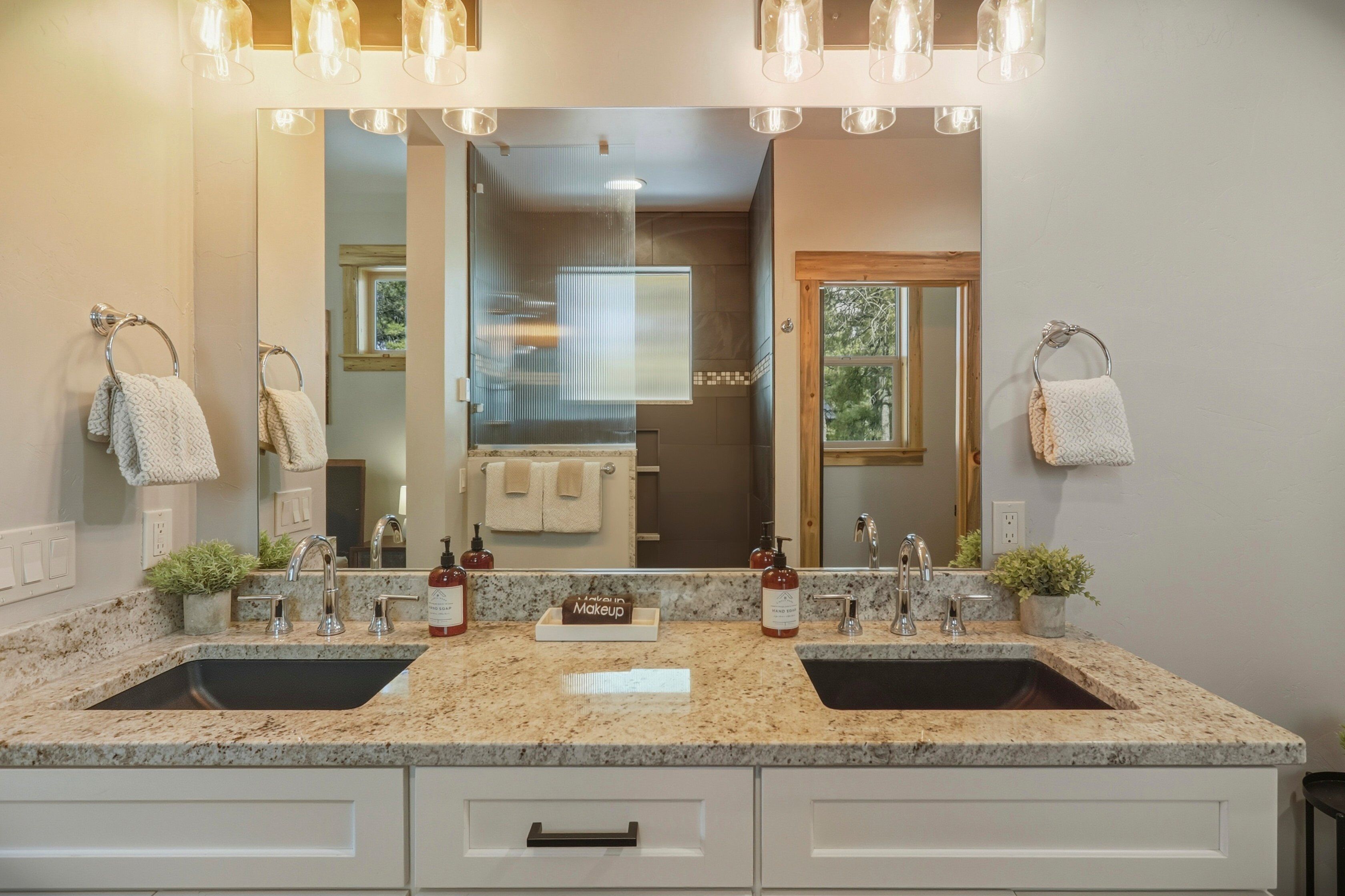 A bathroom with two sinks, a large mirror, and overhead lighting.