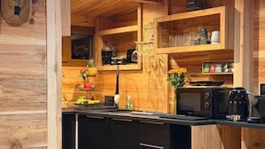 Ein Holzinterieur mit Küchenbereich, der schwarze Schränke, eine Mikrowelle und eine Kaffeemaschine zeigt.