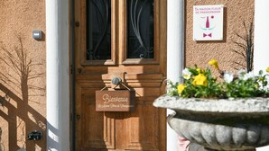 Eine Holztür mit einem 'Bienvenue'-Schild, einem Blumentopf und einem Schild mit der Aufschrift 'La Maison Fleur de Frangipaniers'.