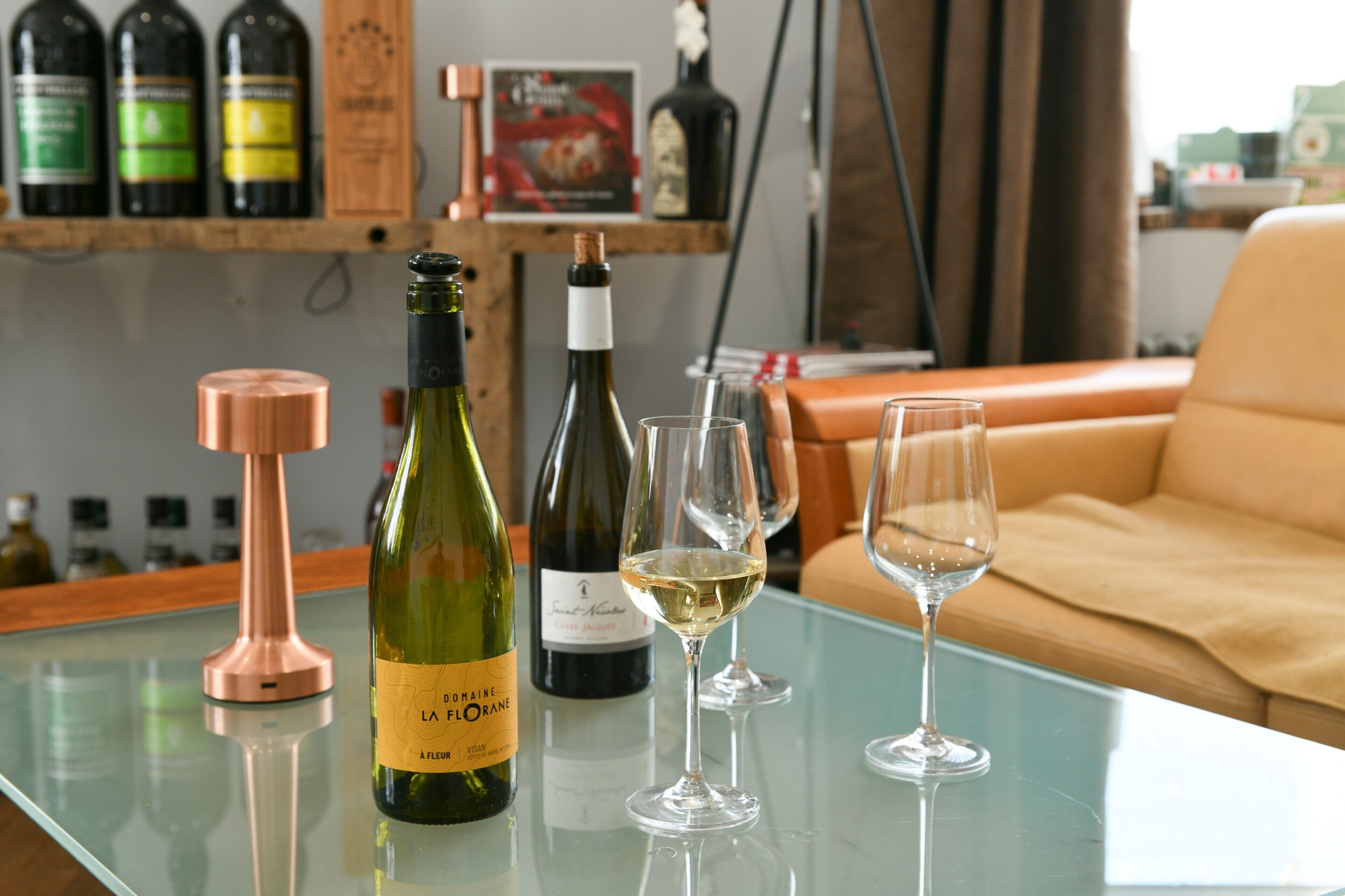 A glass table with wine bottles and glasses.