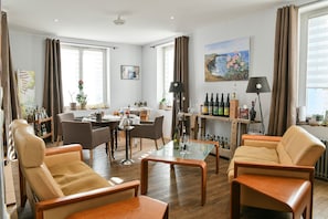 Una sala de estar con sofás de cuero, una mesa de centro de vidrio, una zona de comedor con sillas, un área de cocina con barra y un cuadro en la pared.