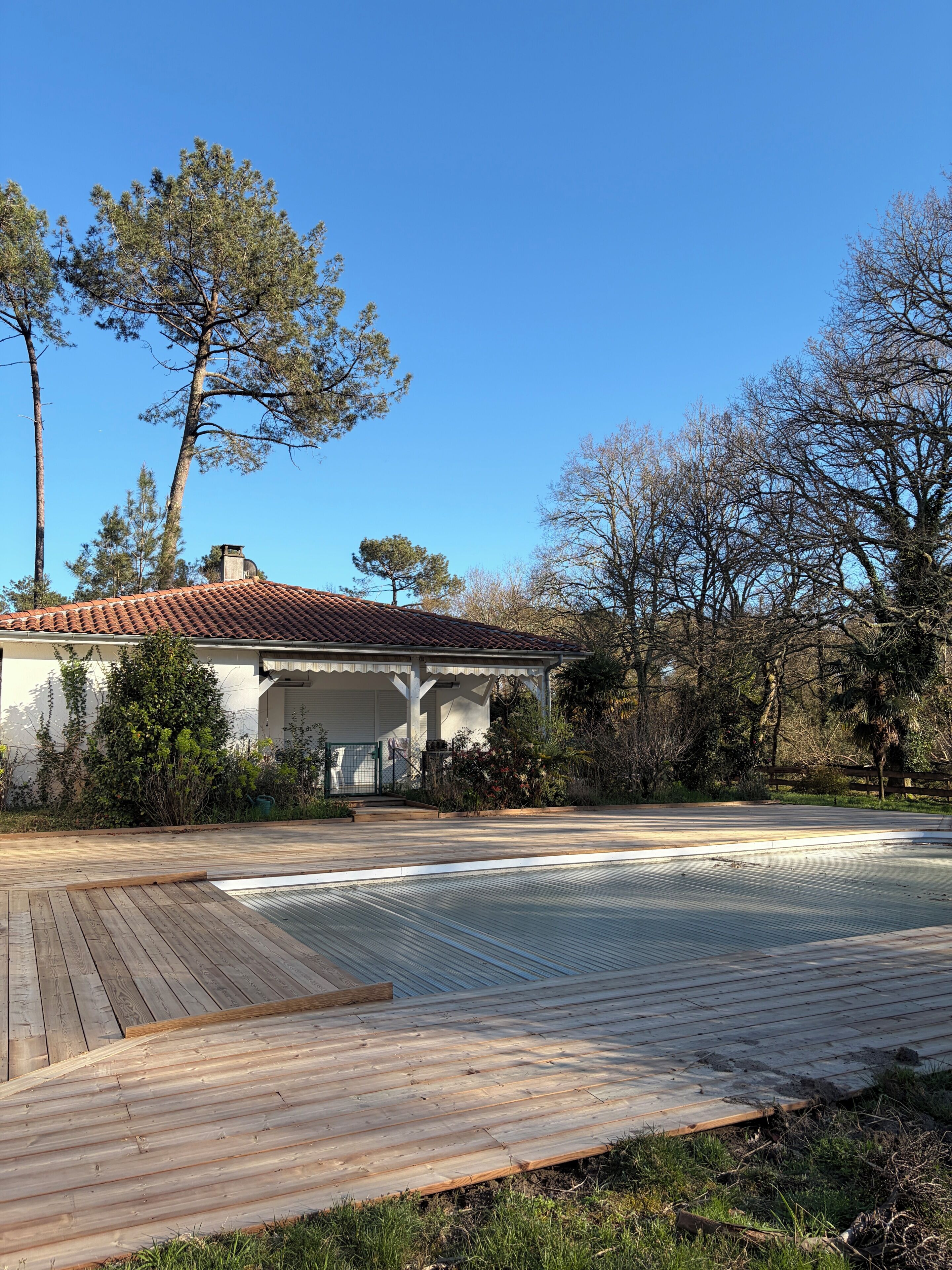 Una casa con techo de tejas, un porche cubierto y una terraza de madera.
