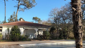 A house with a tiled roof, a wooden deck, and a palm tree. - CAP DE HE' MAIN HOUSE (Lit-et-Mixe)