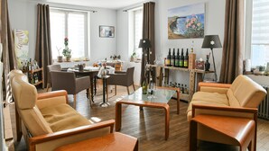 Een woonkamer met leren banken, een glazen salontafel, een eethoek met stoelen, een keuken met een bar en een schilderij aan de muur.