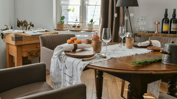 Een eetgedeelte met een houten tafel, stoelen, een lamp en diverse keukenbenodigdheden.