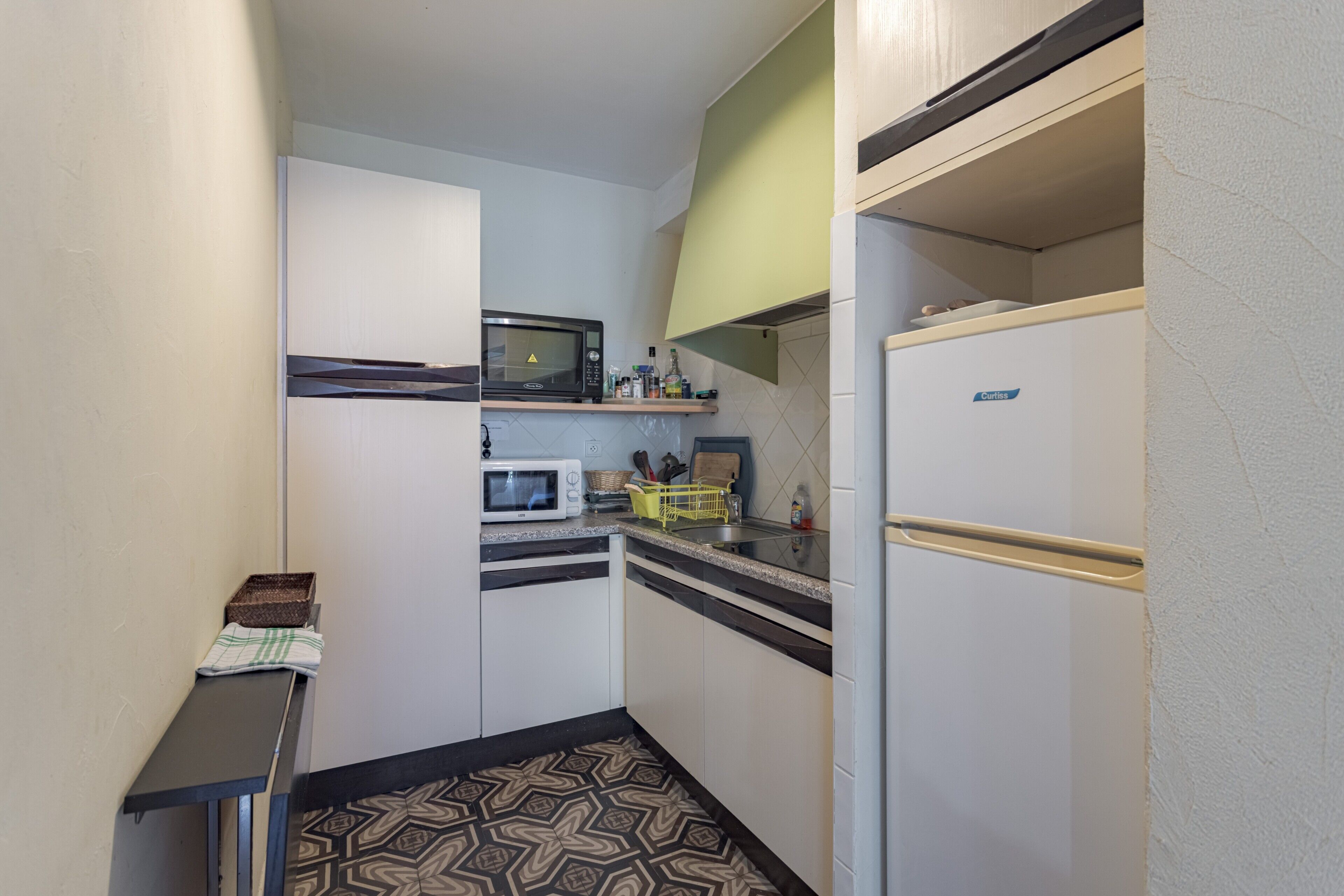 Una cocina compacta con microondas, refrigerador y una pequeña encimera.