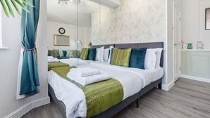 Ein modernes Schlafzimmer mit einem großen Bett, einem Spiegel und einer Wand in Grüntönen.