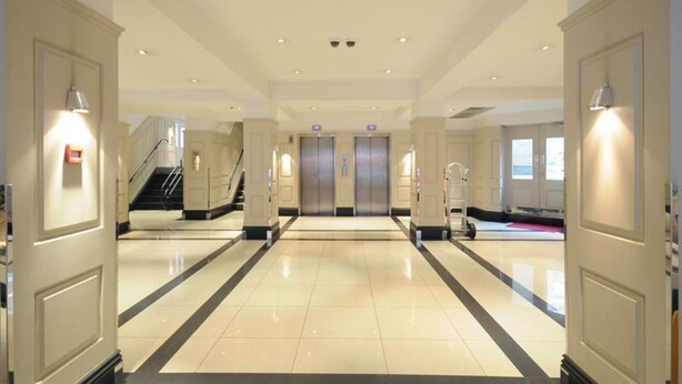 Eine Hotte lobby mit einem zentralen Aufzug, einer Treppe und einer Rezeption.