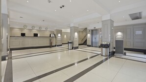 Eine geräumige Lobby mit hoher Decke, eingelassener Beleuchtung und einem sauberen, gefliesten Boden.