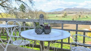 A balcony with a round table, two chairs, and three potted plants. - Charming Guest Room «Dali» (Saint-Genix-les-Villages)