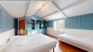 A room with two beds, a built-in bookshelf, and a window providing natural light.