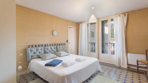 Una camera da letto con un letto, un comodino, una lampada, una sedia e vista sull'esterno.