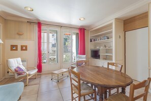 A dining area with a wooden table and chairs, a television, and a bookshelf.