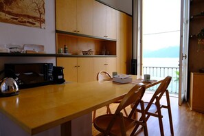 Une cuisine avec des meubles de rangement en bois, une table en bois et une vue sur l’extérieur.