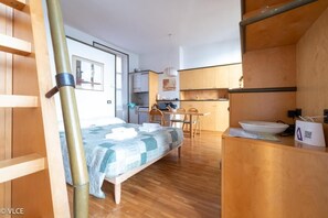 A compact hotel room with a bed, a small kitchenette, and a wooden desk. - La casa di Anna - Studio Apartment, Sleeps 3 (Varenna)