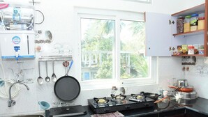 Eine Küche mit Gasherd, Spüle, hängenden Küchenutensilien und einem Fenster mit Blick auf Grünfläche.