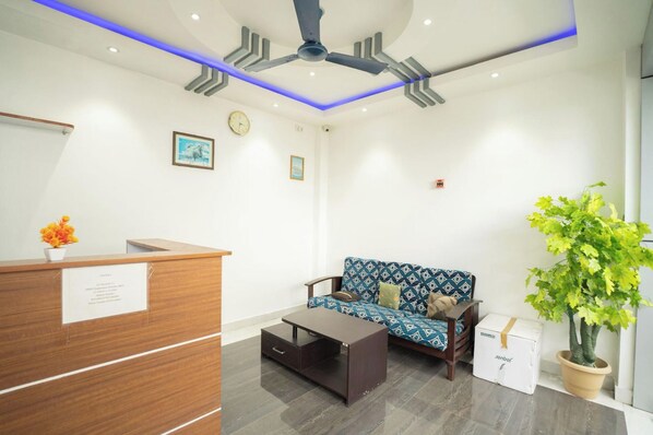 A reception area with a wooden desk, a sofa, a coffee table, and a potted plant.