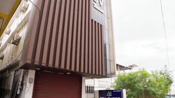 A building with a vertical striped facade and a closed red shutter door.