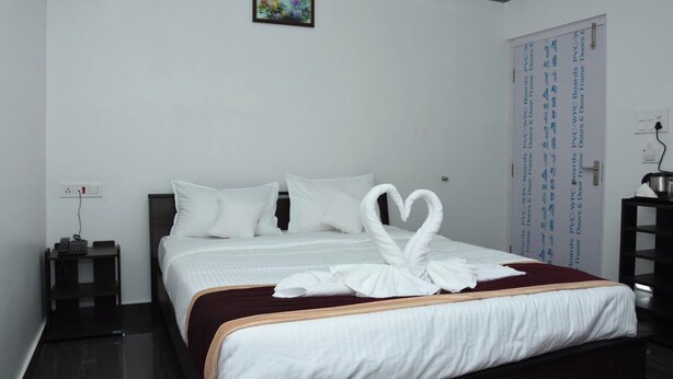 Ein Hotelzimmer mit einem ordentlich bezogenen Bett, einem Nachttisch mit Telefon und einem Wandbild.