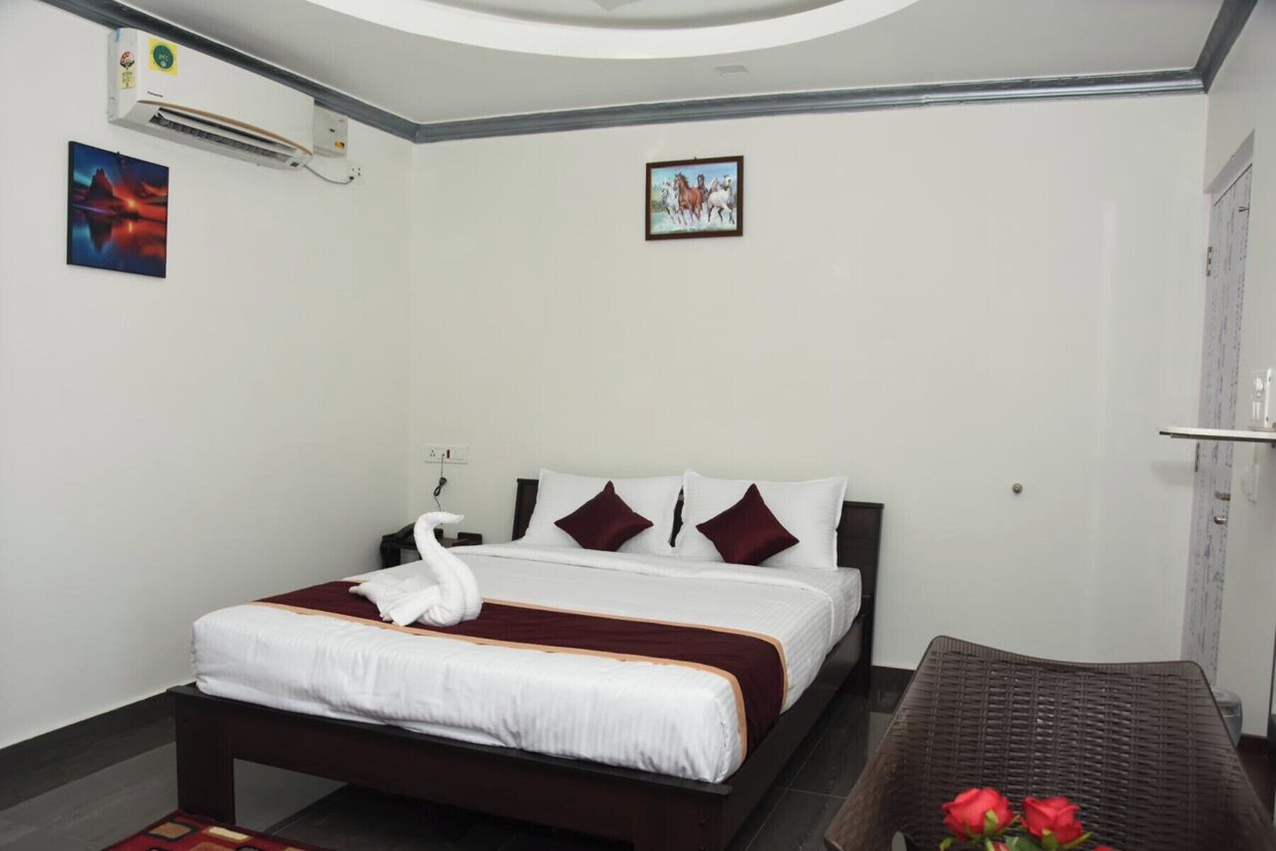 A hotel room with a bed, a chair, and a wall-mounted air conditioner.