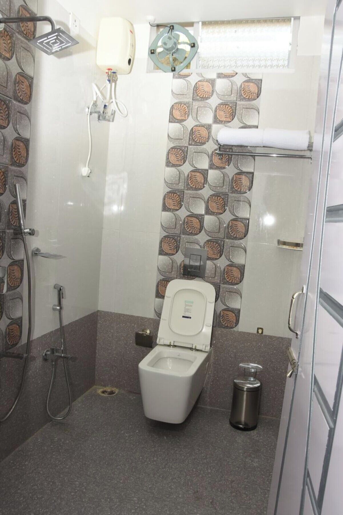 A small, modern bathroom with a toilet, a shower, and a hand dryer.