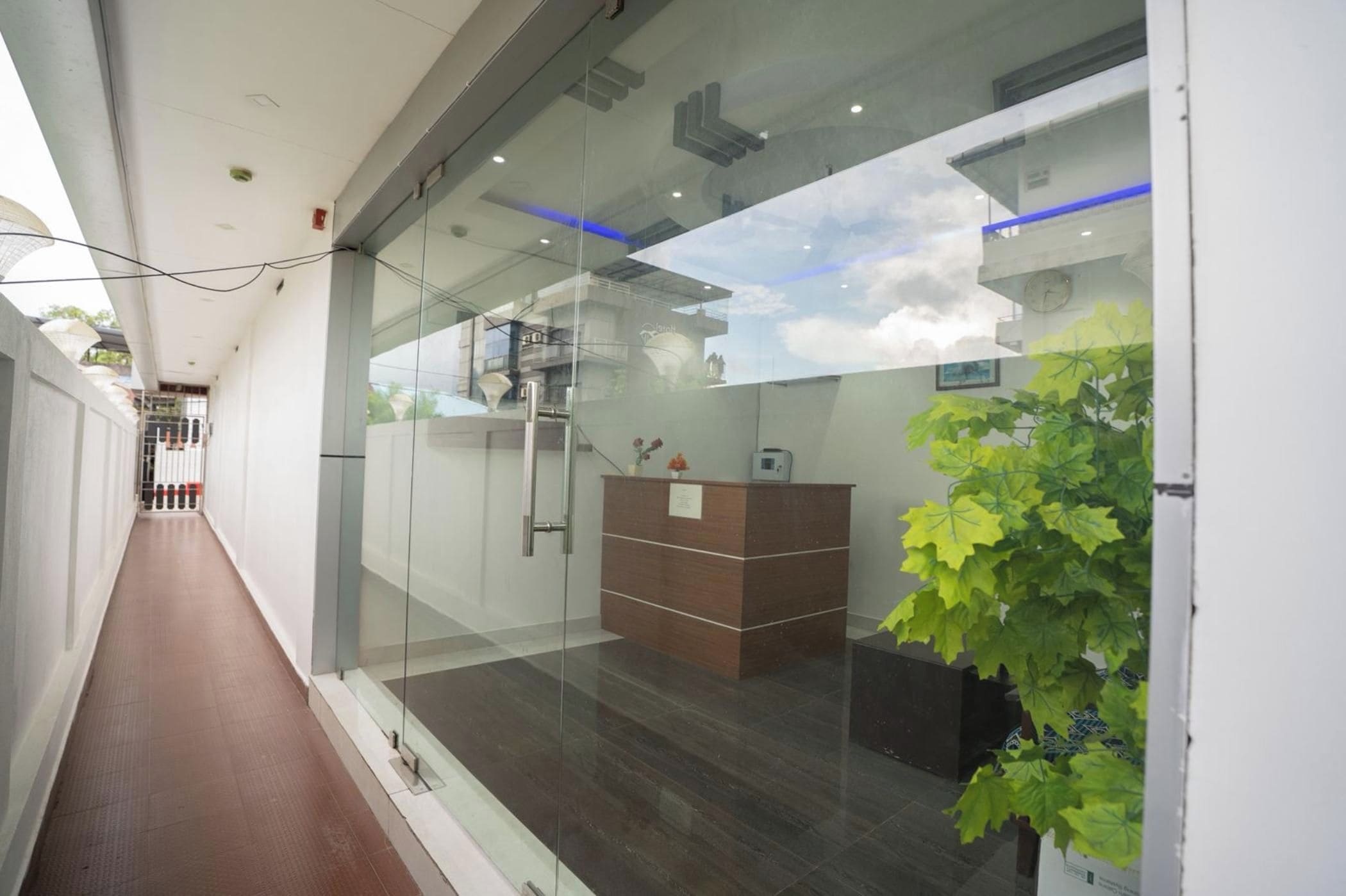 A modern reception area with glass walls, a reception desk, and a plant.