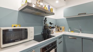Cozinha com micro-ondas, fogão, forno e uma prateleira com diversos frascos.