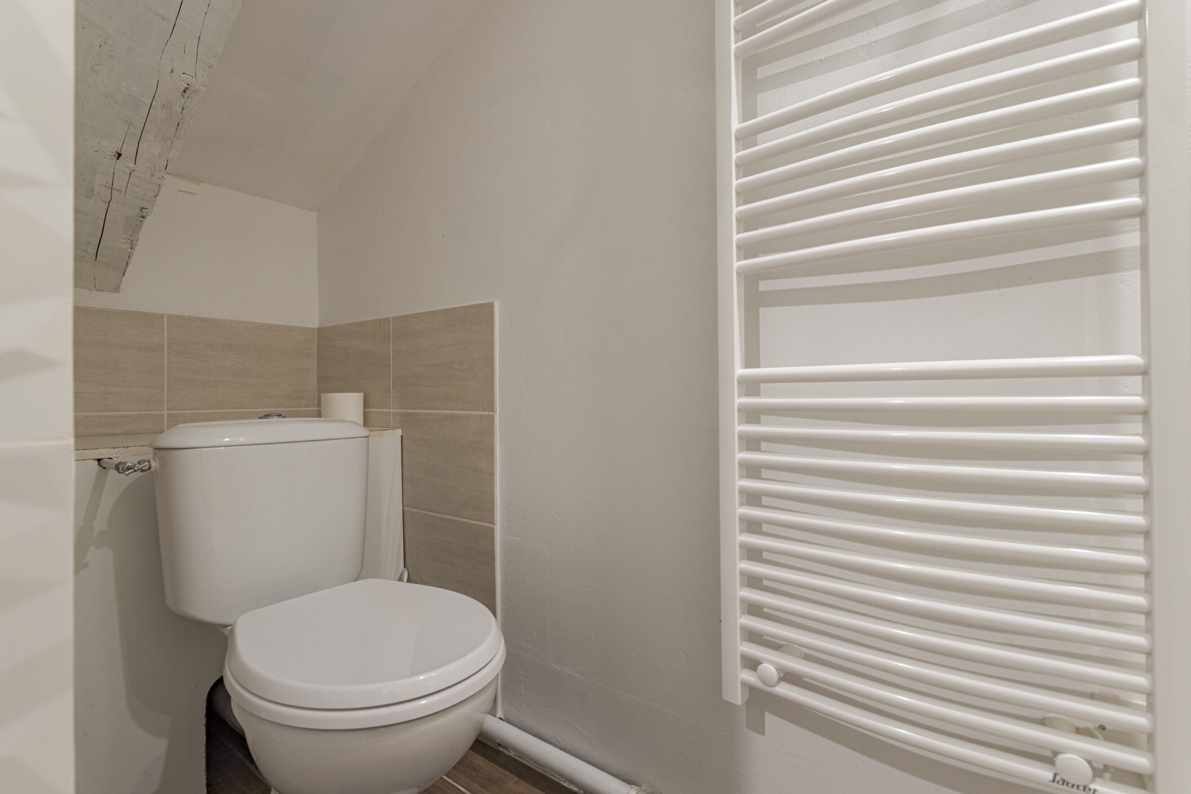 A bathroom with a toilet, a towel rack, and a radiator.