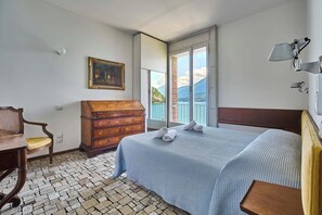 A bedroom with a bed, wooden dresser, chair, and a painting on the wall.