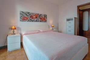 Une chambre à coucher comprenant un lit, deux tables de chevet, une commode, une coiffeuse et une porte.