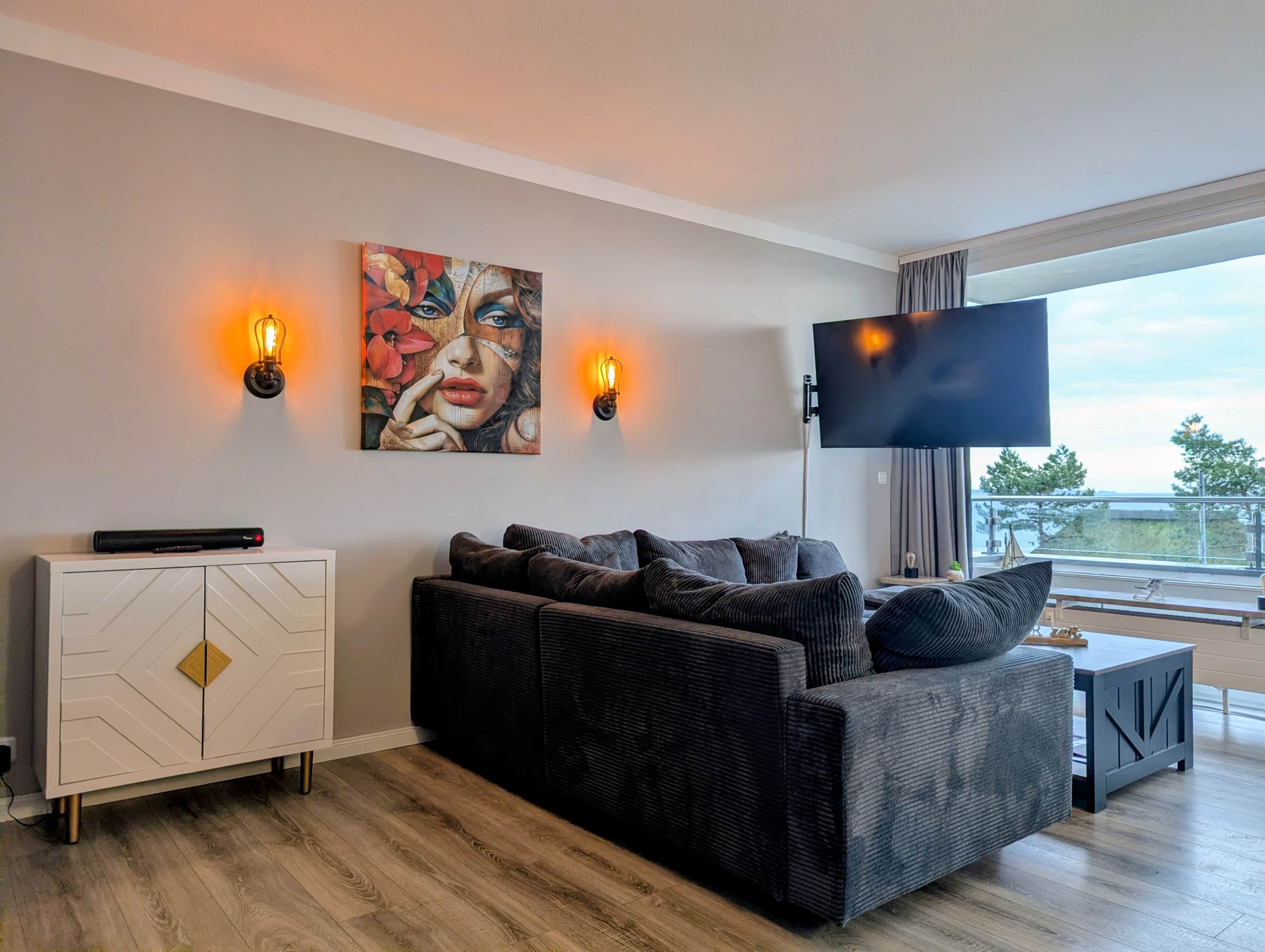 Ein modernes Wohnzimmer mit einer Couch, einem Schrank, einem Flachbildfernseher und einem Bild an der Wand.