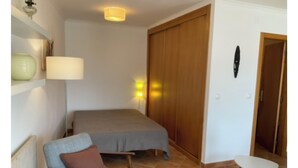 A bedroom with a bed, a chair, a small table, and a wardrobe. - Cantinho da Luísa (Coimbrã- Atouguia da Baleia)