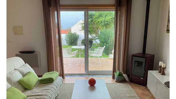 A living room with a sofa, a coffee table, a TV, and a view of the outdoors. - Cantinho da Luísa (Coimbrã- Atouguia da Baleia)