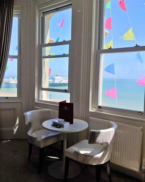 Une pièce avec vue sur la mer, une table avec un livre et deux chaises.