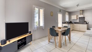 A modern living room with a flat-screen TV, dining table, and chairs. - Le petit mas du vigné (Saint-Pargoire)