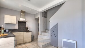 A modern kitchen with a built-in stove, a wooden cabinet, and a staircase leading to another level. - Le petit mas du vigné (Saint-Pargoire)