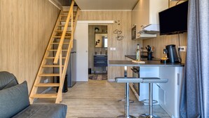 Une cuisine moderne avec un escalier en bois, un coin bar et un téléviseur à écran plat.