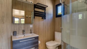 Une salle de bain moderne avec un mur en bois, un lavabo avec un miroir, des toilettes et une douche à parois de verre.
