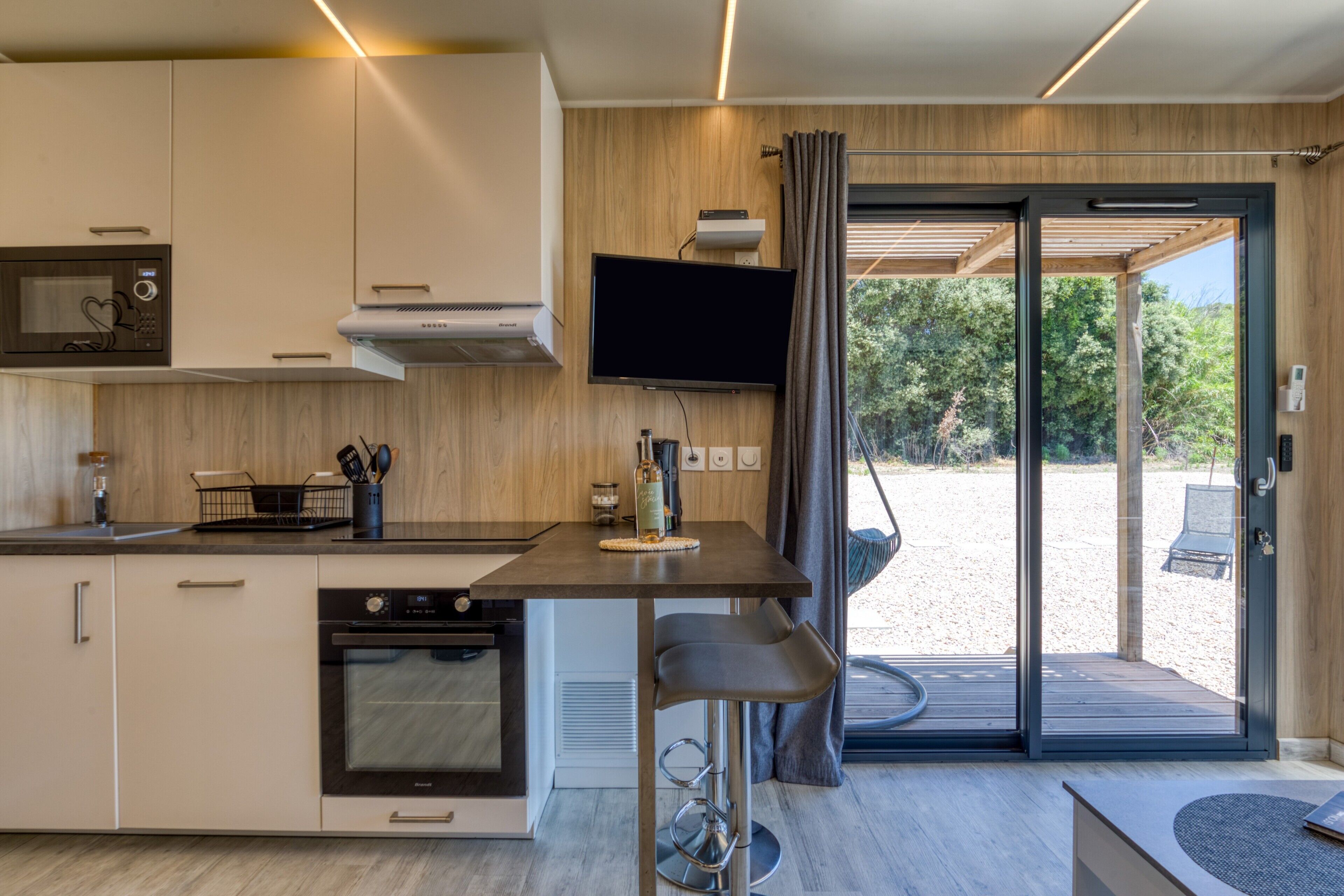 Een moderne keuken met een flatscreen televisie, een magnetron en een inbouwoven.