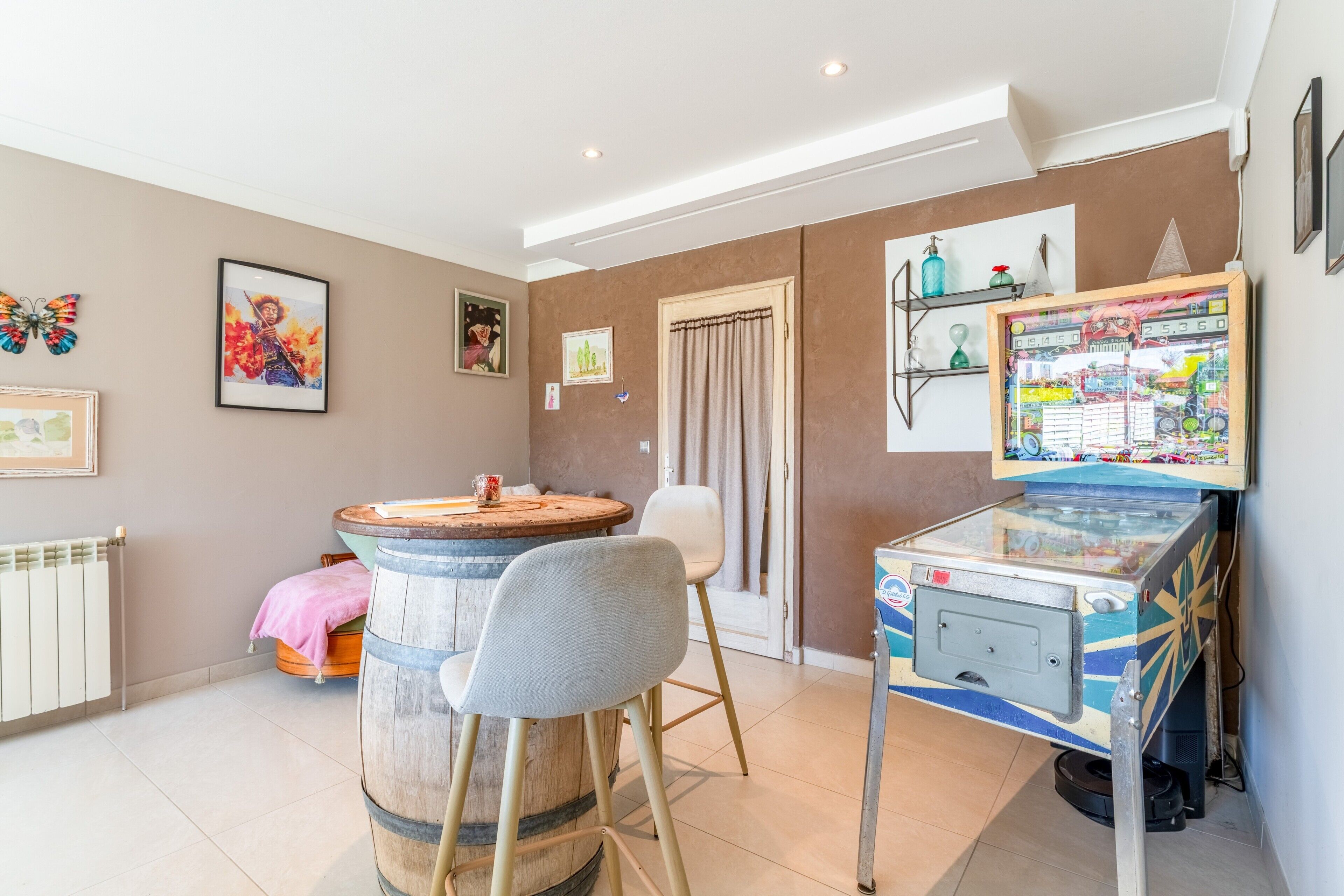 A room with a wooden barrel, a chair, a table, a vending machine, and a radiator.
