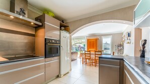 A modern kitchen with stainless steel appliances, a dining area with wooden furniture, and a view of the outdoors.