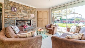 A living room with a stone wall, fireplace, two sofas, and a glass coffee table.