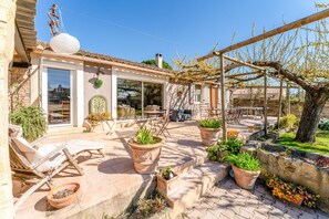 Un pati amb mobles d'exterior, plantes en testos i una pèrgola.