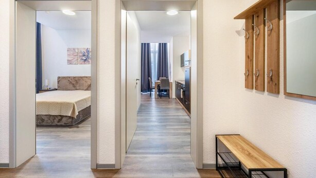 Un pasillo con una cama, un banco y una zona de cocina.