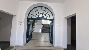 Un pasillo con un reloj, una escalera y señales indicativas.