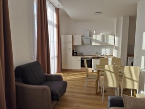 Moderni huoneisto, jossa on olohuone, pieni keittiö ja ruokailutila.