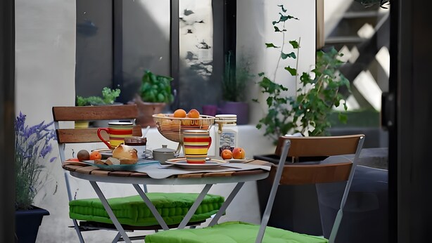 Une table à manger avec des chaises, un saladier de fruits et une plante en pot.