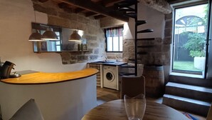 Une cuisine rustique avec un comptoir en bois, un lave-linge et une grande fenêtre donnant sur un paysage verdoyant.